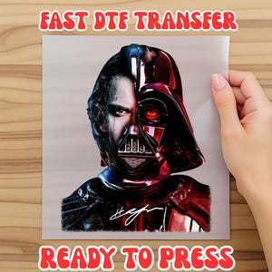 May include: A DTF transfer sheet featuring a split-face graphic of a human male on the left and a black helmeted character with a glowing red eye on the right. The text FAST DTF TRANSFER and READY TO PRESS appears in red above and below the image.