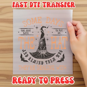 May include: A ready-to-press DTF transfer sheet with the text "SOME DAYS YOU JUST HAYE TO PUT ON THE HAT AND REMIND THEM WHO THEY'RE DEALING WITH". The design features a witch hat with a spider web and bats.