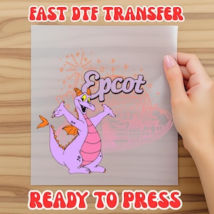 May include: A clear sheet featuring a purple dragon character with orange wings and tail, and the word "Epcot" in a stylized font. The sheet also has the text "FAST DTF TRANSFER" and "READY TO PRESS" in red.