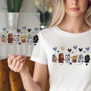May include: White t-shirt featuring a colorful graphic of Star Wars characters holding balloon bouquets. The characters include BB-8, Chewbacca, a Stormtrooper, Yoda, R2-D2, and Darth Vader. The design is repeated on a clear glass panel.