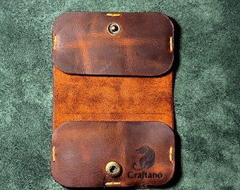 May include: Open leather card holder in shades of brown. The card holder has a snap closure and yellow stitching. The brand name "Craftano" and a bear logo are visible on the bottom flap.