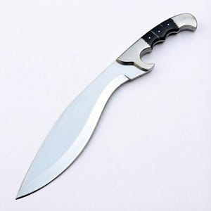 May include: A large, curved blade knife with a polished silver finish. The handle features a black and silver design with a bottle opener. The knife has a sharp, pointed tip and a curved blade, suggesting a hunting or utility tool.