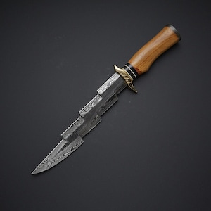 May include: A handcrafted knife with a wooden handle and a patterned steel blade. The blade has a unique, angular design. The handle is a light brown color, and the knife has a brass bolster.