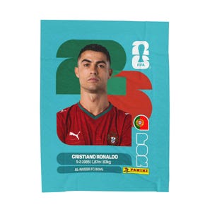 May include: A rectangular trading card featuring a portrait of Cristiano Ronaldo in a red jersey. The background is light blue with large green and red numbers. Text includes his name, birth date 5-2-1985, 1.87m, 83kg, Al-Nassr FC, and Panini.
