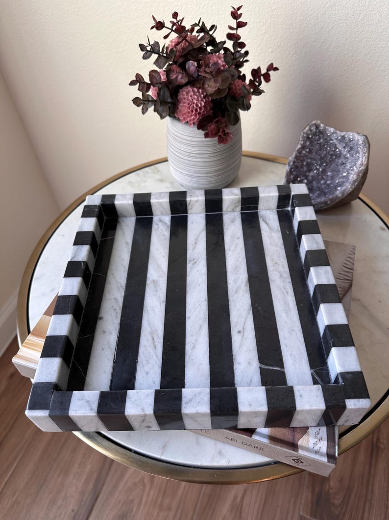 May include: A rectangular tray crafted from polished stone featuring a bold, high-contrast pattern of vertical black and white stripes. The tray has raised edges with a matching striped design that continues along the perimeter of the frame.