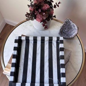 May include: A rectangular tray featuring a bold, alternating vertical stripe pattern in black and white. The tray has raised edges with a matching striped design, constructed from a smooth, polished stone material with visible natural veining.