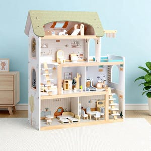May include: A multi-story wooden dollhouse with a green shingled roof and a light blue background. The dollhouse features multiple rooms with miniature furniture, including a living room, bedroom, and bathroom. The exterior is painted white with decorative tree and arch details.