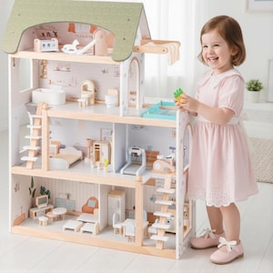 May include: A multi-story wooden dollhouse with a green roof and numerous miniature furniture pieces. The dollhouse features a detailed interior with rooms, including a bedroom, bathroom, and living area. A young child in a pink dress stands next to the dollhouse.
