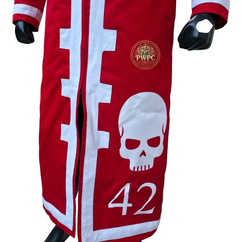 May include: Red garment with white accents and a large white skull graphic. The number 42 is below the skull. The garment has a gold emblem with the letters "PWPC". The sleeves have white trim.