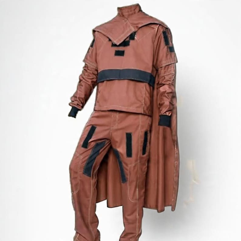 May include: A brown costume with black accents, featuring a jacket with a high collar and cape, and matching pants. The jacket has black patches and a black band across the chest. The pants also have black patches.