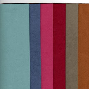 May include: A collection of six rectangular felt fabric sheets arranged side-by-side in a vertical orientation. The colors from left to right are light blue, dark blue, magenta, deep red, taupe, and a warm brown, all featuring a matte texture.