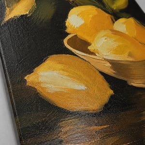 Puede incluir: Una pintura al &oacute;leo sobre lienzo que muestra varios limones de color amarillo brillante con hojas verdes. Los limones est&aacute;n dispuestos en un cuenco de color claro y uno se encuentra por separado sobre una superficie oscura y texturizada.