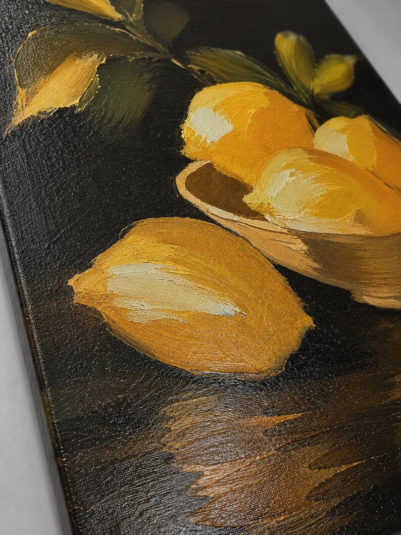 Puede incluir: Una pintura al &oacute;leo sobre lienzo que muestra varios limones de color amarillo brillante con hojas verdes. Los limones est&aacute;n dispuestos en un cuenco de color claro y uno se encuentra por separado sobre una superficie oscura y texturizada.