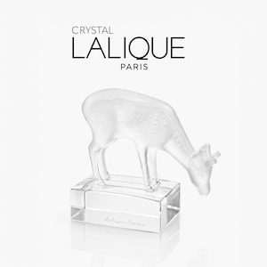Puede incluir: Una figura de cristal transparente de un ciervo pastando sobre una base rectangular. El texto CRYSTAL LALIQUE PARIS está impreso sobre el ciervo, y el texto Lalique France está grabado en la parte frontal de la base de cristal.
