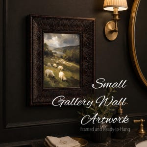 May include: A framed landscape painting featuring a flock of white sheep grazing on a grassy hillside under a cloudy sky. The artwork is enclosed in a dark, ornate, textured frame. The text "Small Gallery Wall Artwork" is visible on the image.