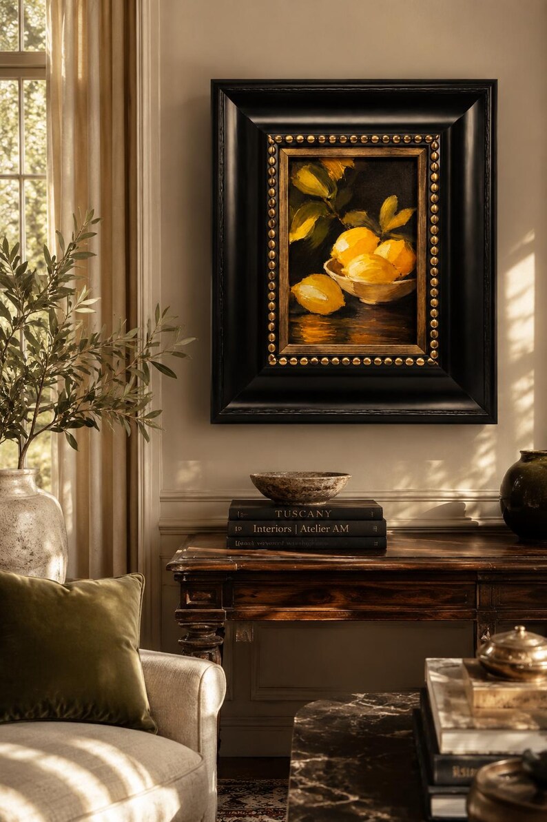 Puede incluir: Una pintura al &oacute;leo de limones amarillos en un cuenco, enmarcada en un marco de madera negra gruesa con adornos de tachuelas doradas. La obra muestra c&iacute;tricos brillantes sobre un fondo oscuro, montada en una pared sobre una mesa consola de madera.