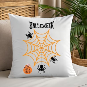 May include: White square pillow with a Halloween theme. The design features an orange spider web with three black spiders, the word "HALLOWEEN" in black, and a small orange "Trick or Treat" candy bucket.