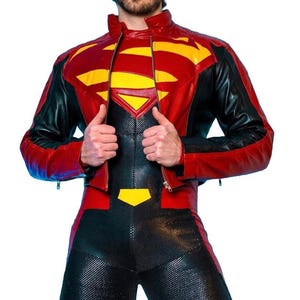 Op de afbeelding: Een rode, gele en zwarte leren jas met het Superman-logo op de borst. De jas heeft een ritssluiting en zwarte mouwen. De outfit bevat een bijpassend zwart en rood jumpsuit.