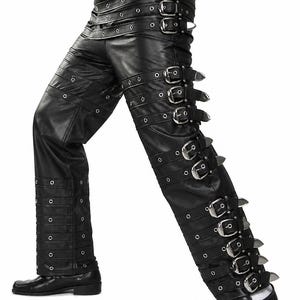 May include: Black leather pants with multiple rows of silver buckles and eyelets. The pants have a straight leg design and are suitable for alternative fashion.