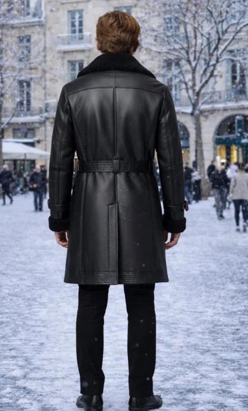 May include: A black leather coat with a black fur collar and a matching belt. The coat is worn over black pants and shoes. The background shows a snowy street scene with buildings and people.