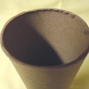 May include: A brown paper cone with a slightly rough texture. The cone is empty and appears to be made from recycled paper.