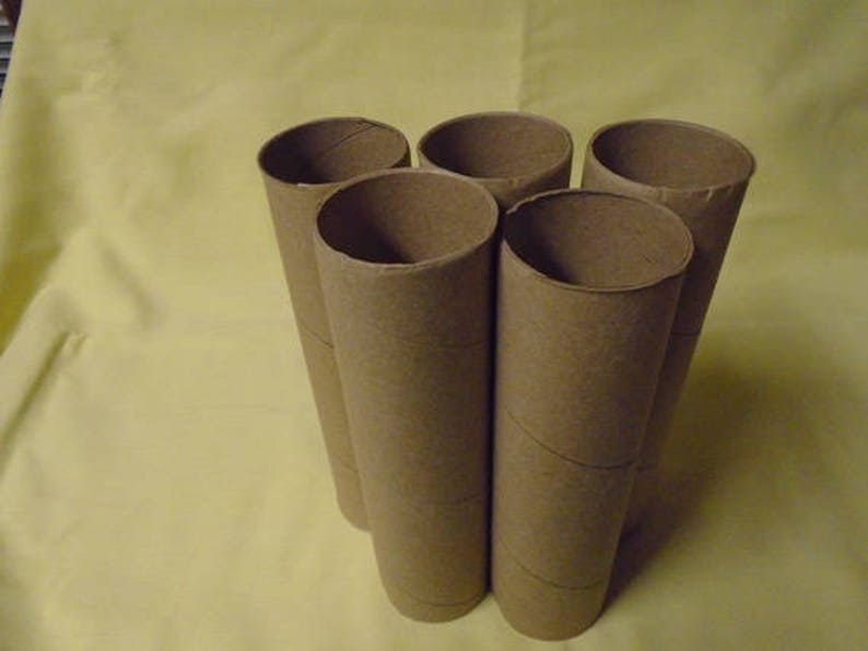 May include: Five brown cardboard tubes, possibly from paper towels or wrapping paper, are stacked in a pyramid shape on a yellow surface.