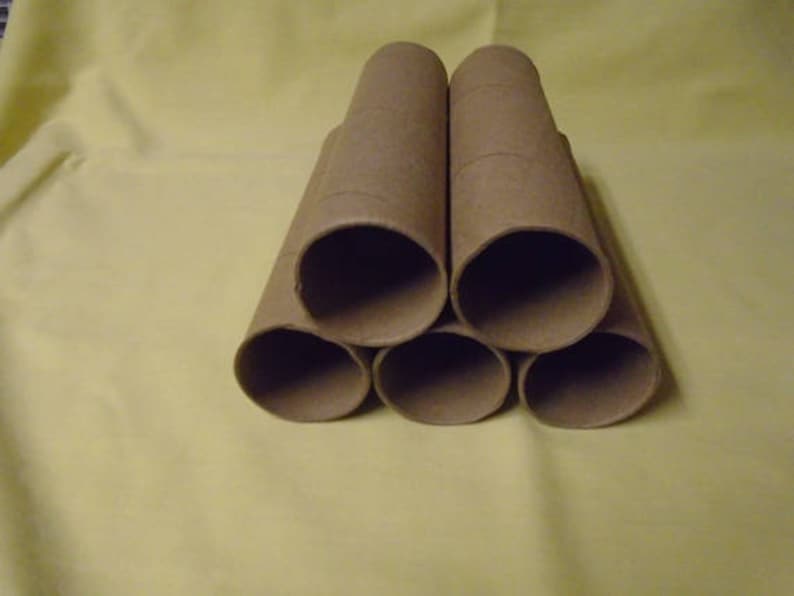 May include: Six brown cardboard tubes stacked in a pyramid shape. The tubes are empty and have a rough texture.