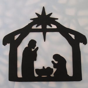 May include: Black silhouette of a nativity scene. The design features a star at the top, a stable, and figures of Mary, Joseph, and baby Jesus. The figures are in a praying position.