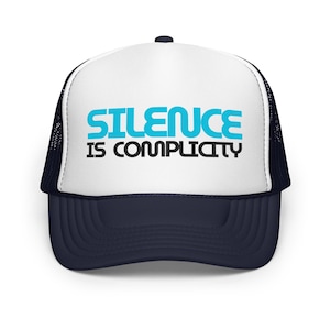 May include: A navy blue and white trucker hat with the text "SILENCE IS COMPLICITY" in turquoise and black. The hat has a mesh back and a curved brim.