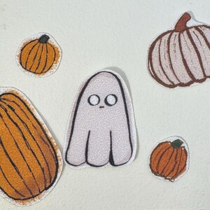 May include: A collection of Halloween-themed stickers featuring pumpkins and a ghost. The pumpkins are orange with brown stems, and the ghost is white with simple black eyes. The stickers are outlined in black.
