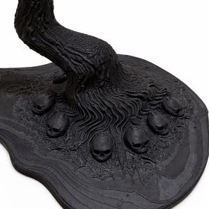May include: A black, stylized sculpture of a tree with a textured trunk and roots. The base features several small skulls. The sculpture has a dark, gothic aesthetic.