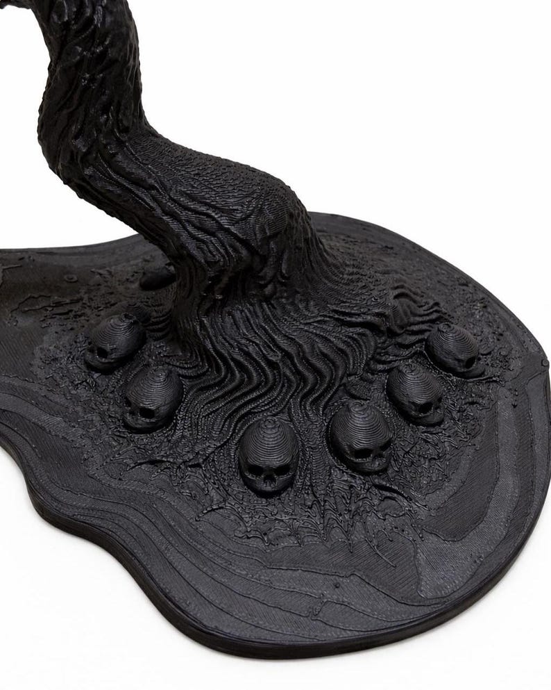 May include: A black, stylized sculpture of a tree with a textured trunk and roots. The base features several small skulls. The sculpture has a dark, gothic aesthetic.