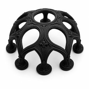 May include: A matte black, dome-shaped stand featuring an intricate, open-work lattice design with arched openings and a circular top aperture. The structure is supported by multiple fluted, pedestal-style feet with detailed relief carvings.