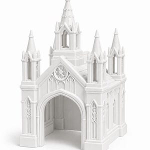 Puede incluir: Modelo de iglesia en miniatura blanca con m&uacute;ltiples agujas y entradas arqueadas. El dise&ntilde;o arquitect&oacute;nico presenta intrincados patrones de ventanas y un campanario central, creando una est&eacute;tica cl&aacute;sica y elegante. El modelo est&aacute; sobre un fondo blanco.