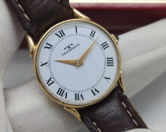 Relógio vintage Technos Dress com corda manual, fabricado na Suíça, mostrador com algarismos romanos, banhado a ouro, 31 mm