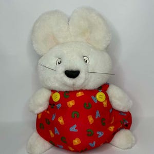 Peut inclure: Une tasse en céramique blanche avec une anse noire et l'inscription "But First, Coffee" en noir, dans une police manuscrite. La tasse est posée sur une surface blanche.