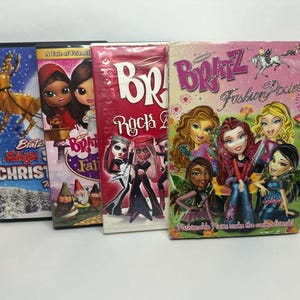 May include: Four Bratz DVD cases are displayed, featuring vibrant graphics. Titles include "Bratz Starrin' Christmas", "A Tale of Friends", "Rock Angelz", and "Fashion Pixiez". The cases showcase colorful illustrations of Bratz characters.