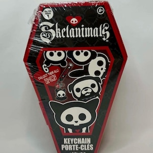 May include: A coffin-shaped Skelanimals keychain box. The box is black with red trim and features various Skelanimals characters in white. Text includes "Skelanimals", "Collect Them All!", and "Keychain".