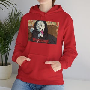 May include: A red hoodie featuring a graphic of the Ghostface mask from the Scream movies, holding a phone and sticking out its tongue. The text "Wazzup!" is below the graphic. The hoodie has a front pocket and a drawstring hood.