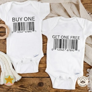 Puede incluir: Dos bodies blancos para bebé con texto negro y diseños de código de barras. Uno dice "COMPRA UNO" y el otro "OBTÉN UNO GRATIS". Ambos tienen el número de código de barras "0 12345 67890 1". Los bodies son de 100% algodón.