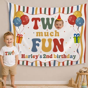 May include: A colorful birthday banner with the text "Two much FUN" and "Harley's 2nd birthday". The banner includes images of balloons, gifts, and a photo of a baby. A young child is standing in front of the banner.
