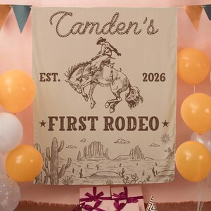 Może przedstawiać: Beżowy baner z tkaniny z brązową ilustracją kowboja ujeżdżającego wierzgającego konia. Tekst głosi "Camden's", "EST. 2026" oraz "FIRST RODEO". Poniżej tekstu znajduje się pustynny krajobraz z kaktusami i formacjami skalnymi.