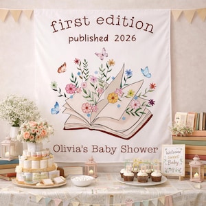 May include: A baby shower scene with a banner that reads "first edition published 2026" and "Olivia's Baby Shower." The banner features an open book illustration with flowers and butterflies. A cake, cupcakes, and decorations are on the table.