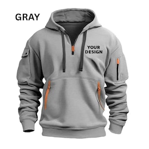 May include: Gray hooded sweatshirt with a half-zip closure and a kangaroo pocket. Features orange zipper accents and pocket details. The text "YOUR DESIGN" is printed on the front. The word "GRAY" is printed at the top.