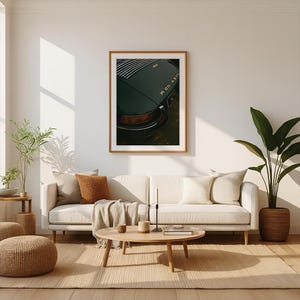 May include: A framed print of a vintage dark green sports car, showcasing the rear with the model name. The image is displayed in a living room setting with a neutral-toned sofa, pillows, and a wooden coffee table.