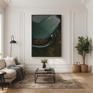 May include: A framed print featuring a close-up of a vintage dark green Porsche. The car's rear, with the word "Porsche" in gold lettering, is the focal point. The image is displayed in a living room setting with a neutral color palette.