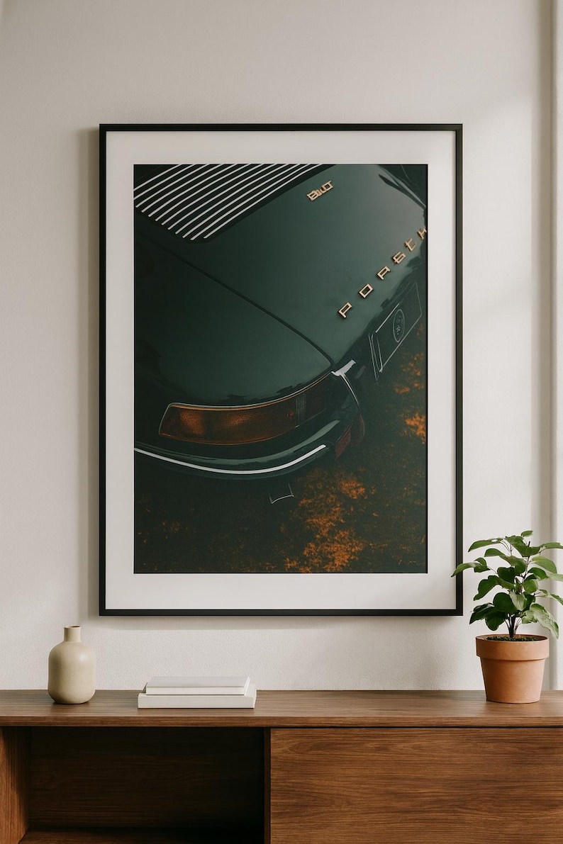 May include: Framed art print featuring a close-up of a vintage dark green Porsche. The car's rear, with the word "Porsche" in gold lettering, is the focal point. The image has a vintage aesthetic, with a focus on the car's design and details.
