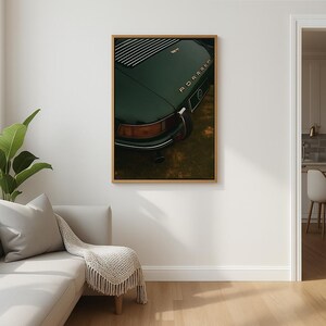 May include: Framed print of a vintage dark green sports car. The rear of the car is visible, showcasing the taillight, exhaust pipe, and the word "Porsche" in gold lettering. The print is in a gold frame.