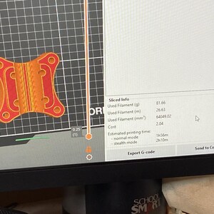 May include: A computer screen displays a 3D model of an orange and red object with a complex design. The screen also shows "Sliced Info" including filament usage and estimated printing time.