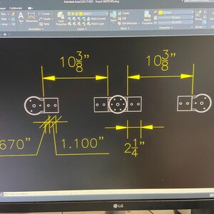 May include: A technical drawing on a black screen, featuring a detailed mechanical design. Dimensions are provided in inches: 10 3/8", 0.670", 1.100", and 2 1/4". The design includes circular and rectangular shapes with multiple holes.